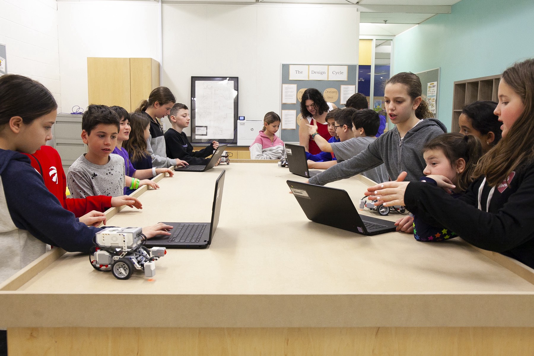 A group of students working on laptops in small groups as they learn about robotics and programming with Lego robotics.