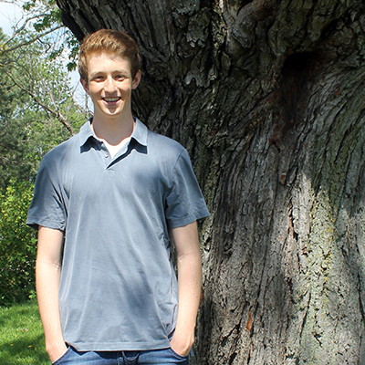 A headshot of Max Debow standing in front of a tree.