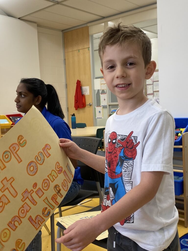 A Leo Baeck student holding a sign encouraging donations.