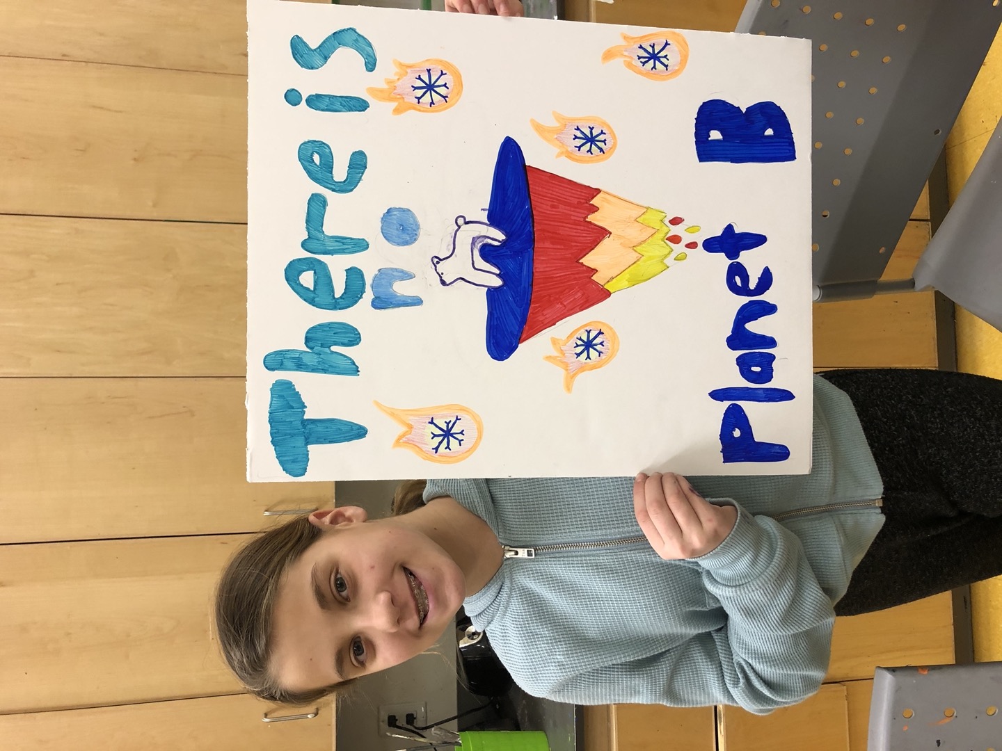 A young student holding up a sign that says "There is no Planet B".